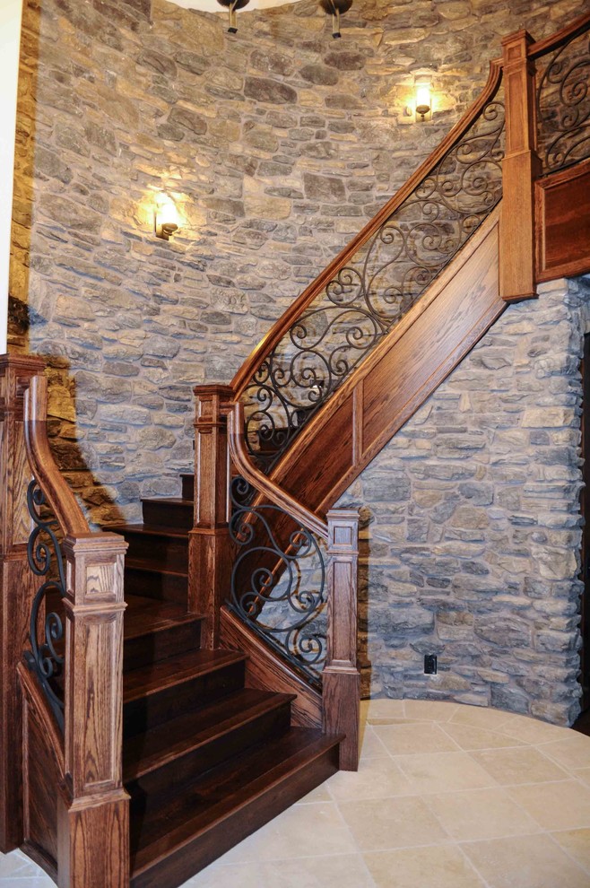 Photo of a large traditional wood curved staircase in Other with wood risers and metal railing.