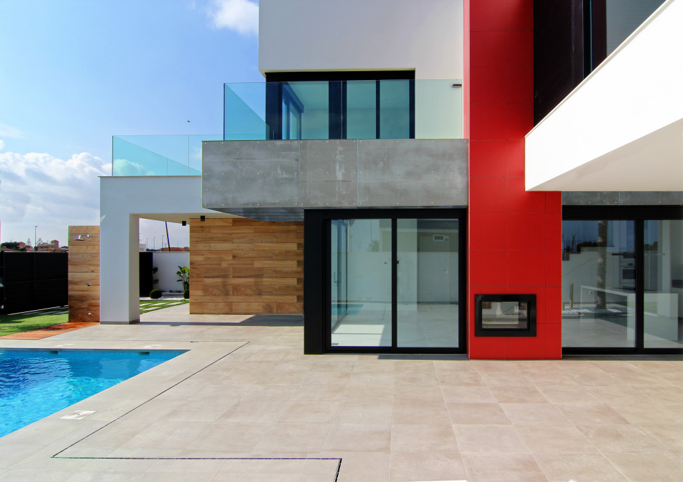 Moderne Terrasse mit Kamin und Glasgeländer in Sonstige