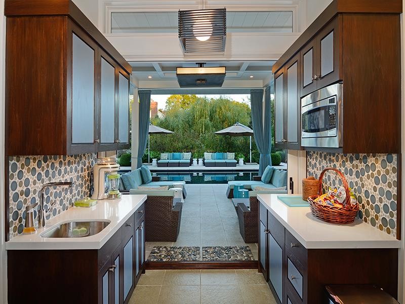 This is an example of a small traditional galley separate kitchen in New York with no island, glass-front cabinets, medium wood cabinets, recycled glass benchtops, multi-coloured splashback, mosaic tile splashback, stainless steel appliances, an undermount sink and porcelain floors.