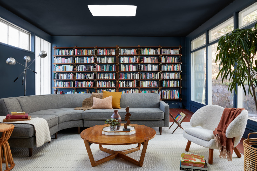 Midcentury living room in New York with a library, blue walls and red floor.