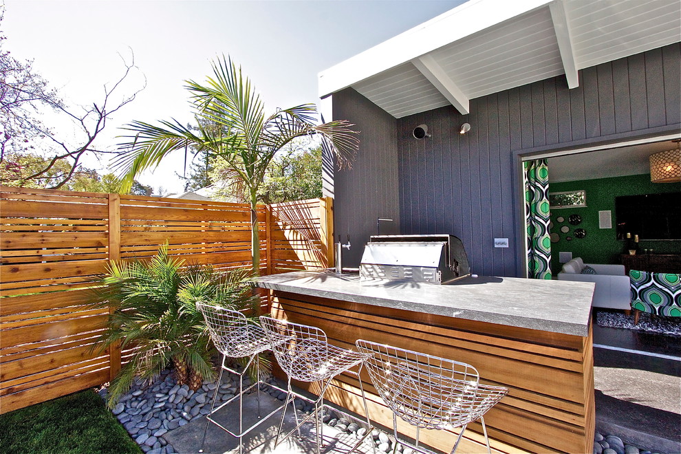 Photo of a small midcentury backyard patio in San Francisco with an outdoor kitchen, stamped concrete and a roof extension.