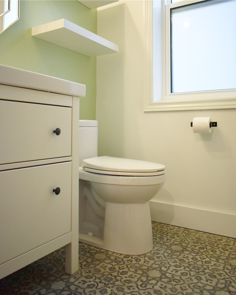 Photo of a small transitional powder room in Vancouver with flat-panel cabinets, white cabinets, a one-piece toilet, green walls, linoleum floors, grey floor, white benchtops, an integrated sink and engineered quartz benchtops.