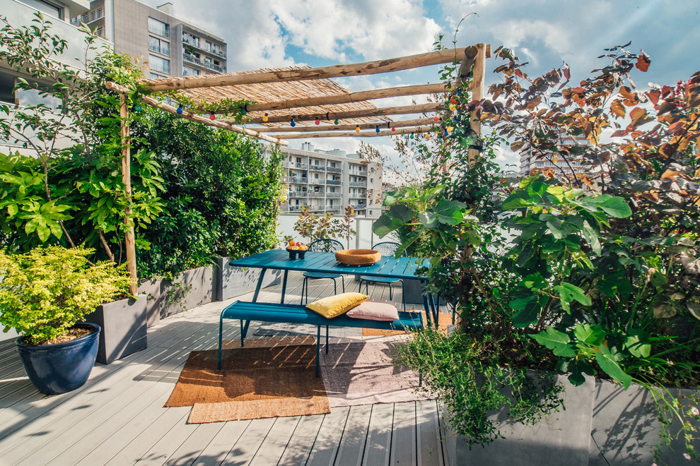 This is an example of an expansive backyard patio in Paris with a container garden, decking and a pergola.