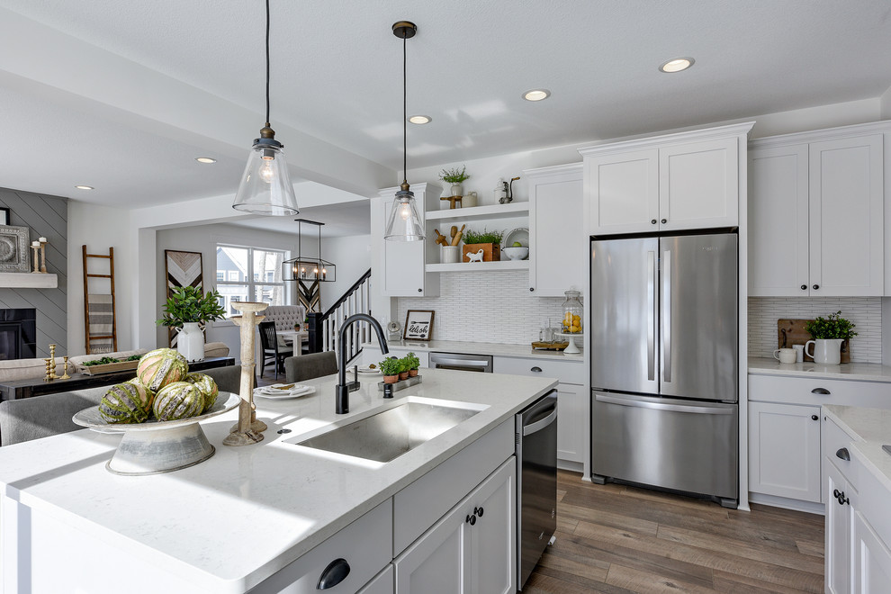 Small country u-shaped kitchen in Minneapolis with an undermount sink, shaker cabinets, white cabinets, quartzite benchtops, white splashback, ceramic splashback, stainless steel appliances, laminate floors, with island, grey floor and white benchtop.