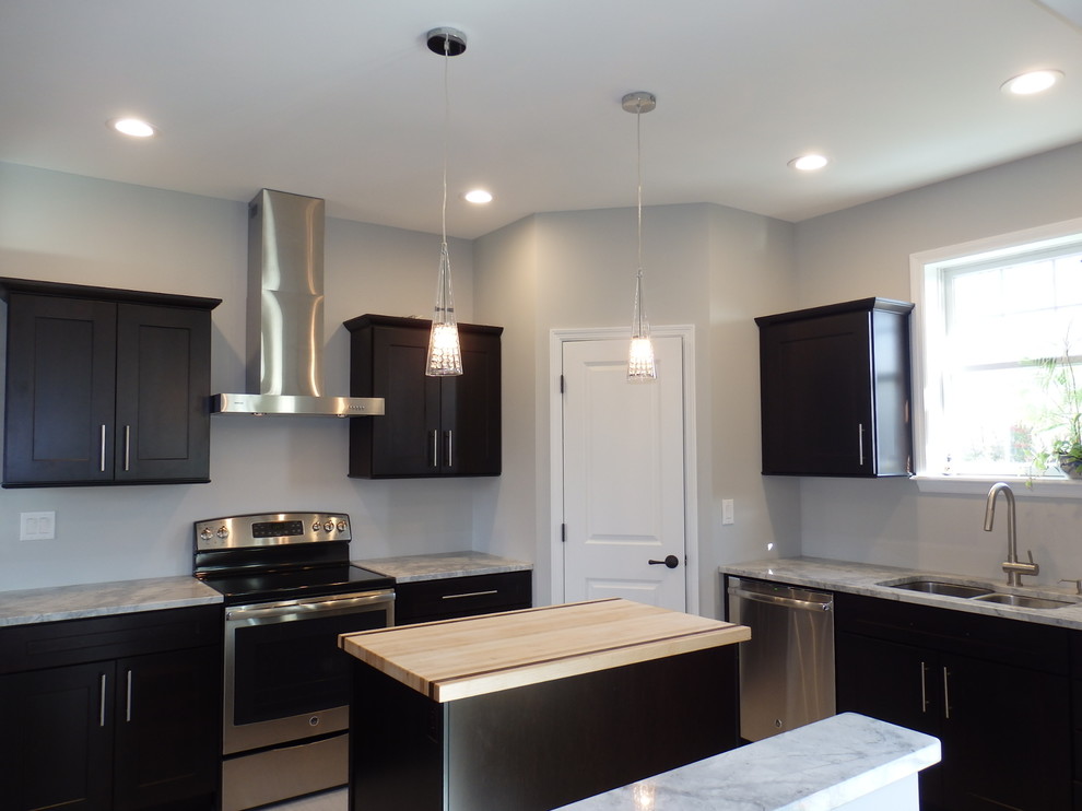This is an example of a contemporary kitchen in Burlington with an undermount sink, recessed-panel cabinets, dark wood cabinets, granite benchtops, stainless steel appliances, porcelain floors and with island.