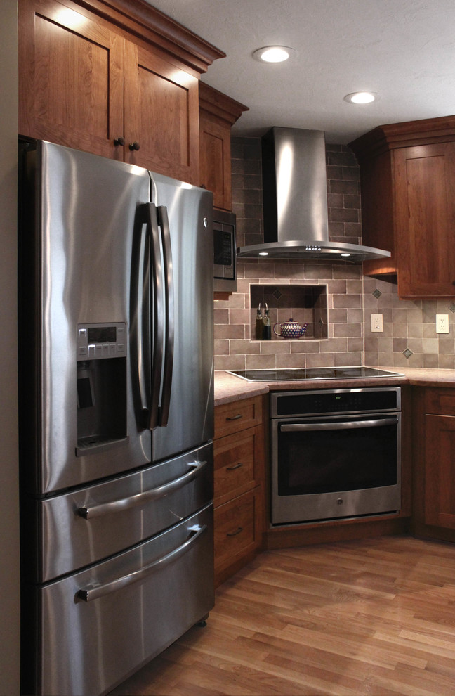 Inspiration for a large transitional u-shaped light wood floor eat-in kitchen remodel in Boston with an undermount sink, shaker cabinets, medium tone wood cabinets, quartz countertops, gray backsplash, porcelain backsplash, stainless steel appliances and a peninsula