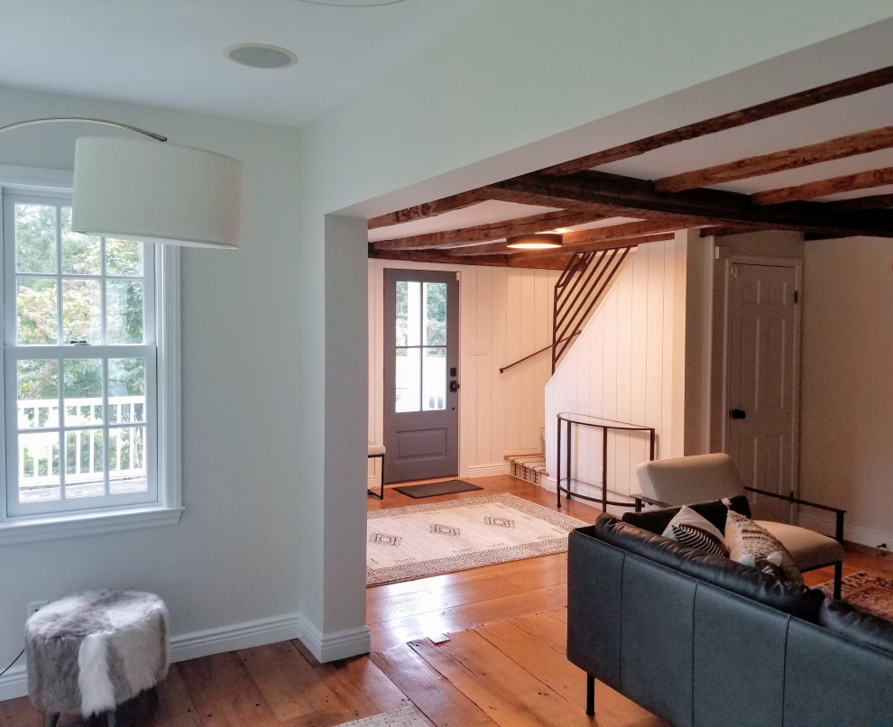 Kleines Foyer mit grauer Wandfarbe, braunem Holzboden, Einzeltür, grauer Haustür, braunem Boden und freigelegten Dachbalken in New York