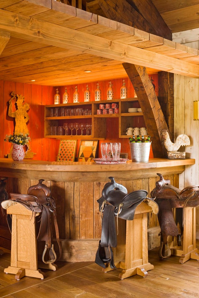 Country seated home bar in New York with open cabinets, medium wood cabinets and medium hardwood floors.