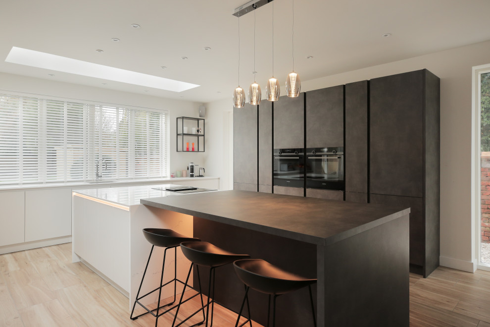 Mid-sized contemporary l-shaped kitchen in Other with an undermount sink, flat-panel cabinets, black appliances, light hardwood floors, with island, beige floor, white benchtop and grey cabinets.