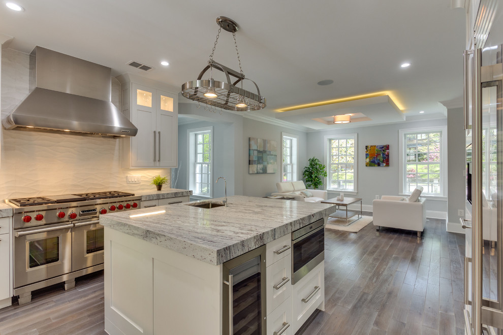 Inspiration for a large transitional l-shaped medium tone wood floor open concept kitchen remodel in DC Metro with a double-bowl sink, shaker cabinets, white cabinets, marble countertops, white backsplash, porcelain backsplash, stainless steel appliances and an island