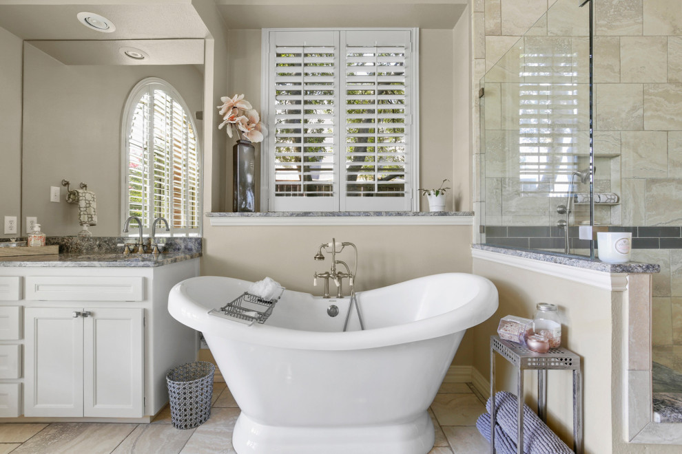 Design ideas for a traditional bathroom in Dallas with recessed-panel cabinets, white cabinets, a freestanding tub, beige tile, beige walls, an undermount sink, beige floor and grey benchtops.