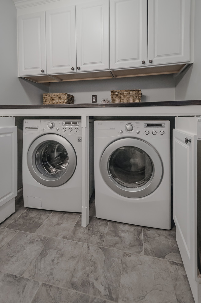 This is an example of a mid-sized traditional utility room in Bridgeport with raised-panel cabinets, white cabinets, laminate benchtops, blue walls, porcelain floors and a side-by-side washer and dryer.