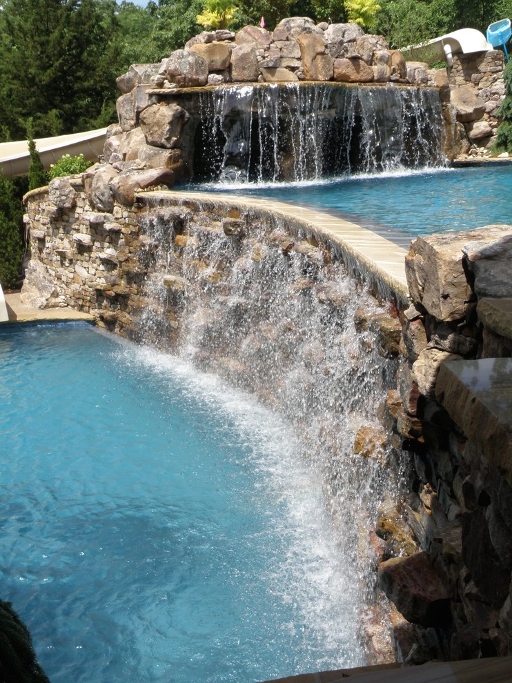 Inspiration for a mid-sized arts and crafts backyard custom-shaped pool in Kansas City with a water feature.