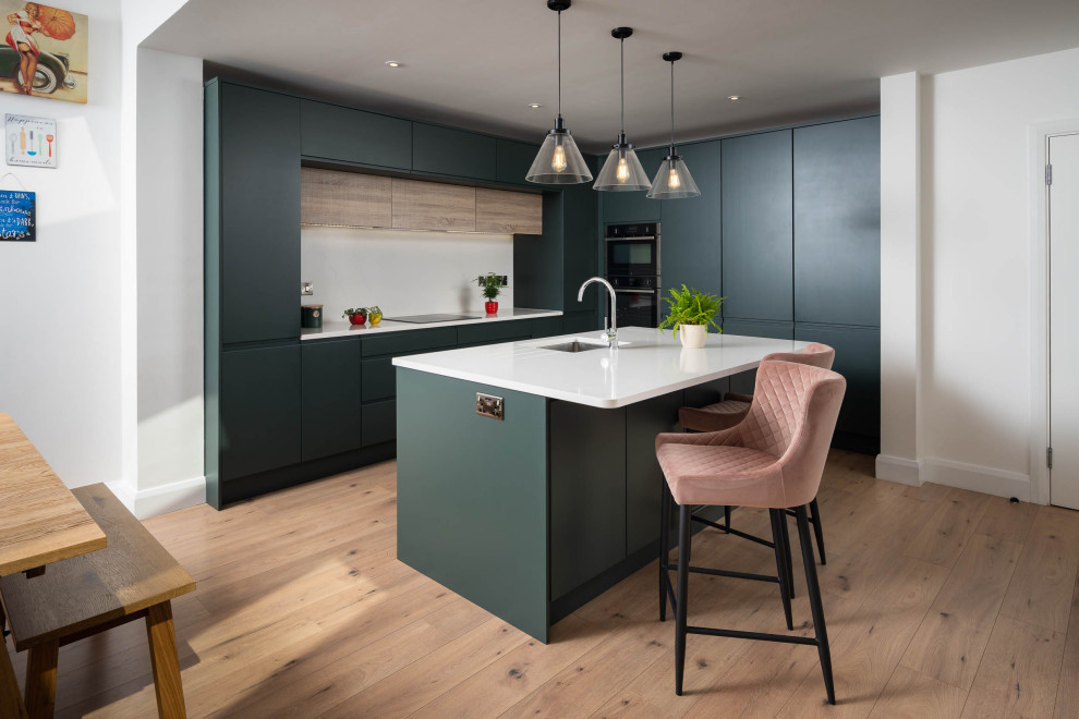 Mid-sized modern l-shaped eat-in kitchen in Dublin with a single-bowl sink, flat-panel cabinets, green cabinets, quartzite benchtops, white splashback, granite splashback, with island and white benchtop.