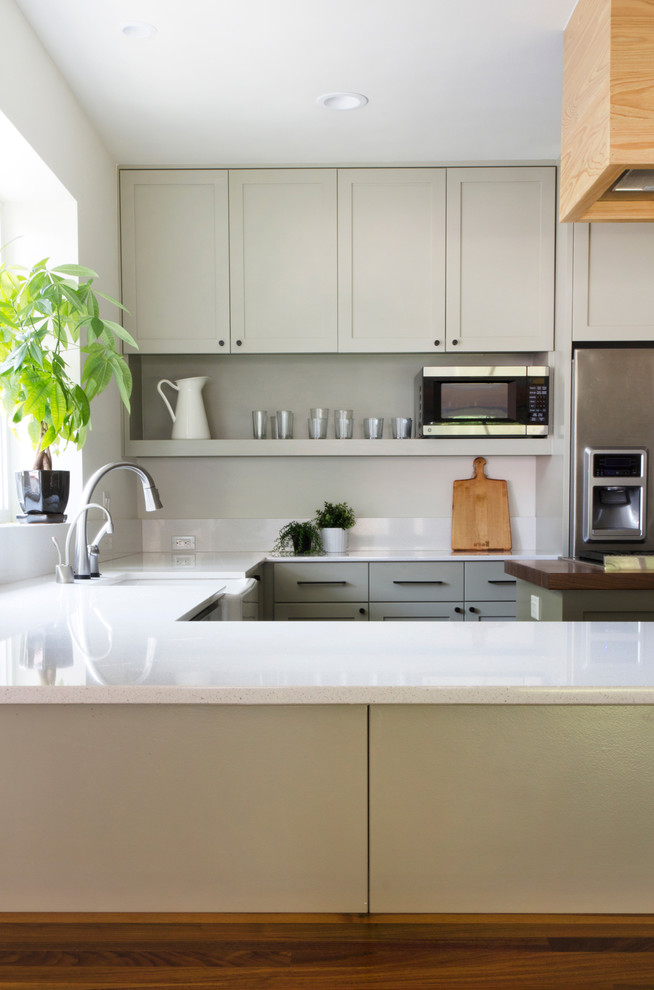 Open concept kitchen - transitional u-shaped dark wood floor open concept kitchen idea in Austin with a farmhouse sink, shaker cabinets, green cabinets, wood countertops, white backsplash, stone slab backsplash, stainless steel appliances, white walls and an island