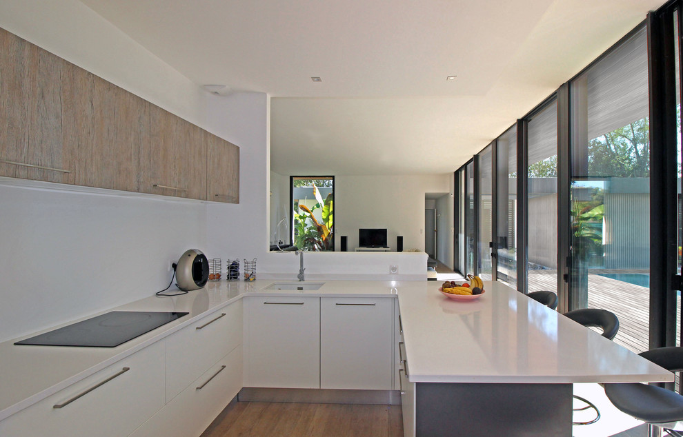 Photo of a mid-sized contemporary u-shaped open plan kitchen in Toulouse with an integrated sink, beaded inset cabinets, white cabinets, quartzite benchtops, white splashback, panelled appliances, ceramic floors, with island, brown floor and white benchtop.