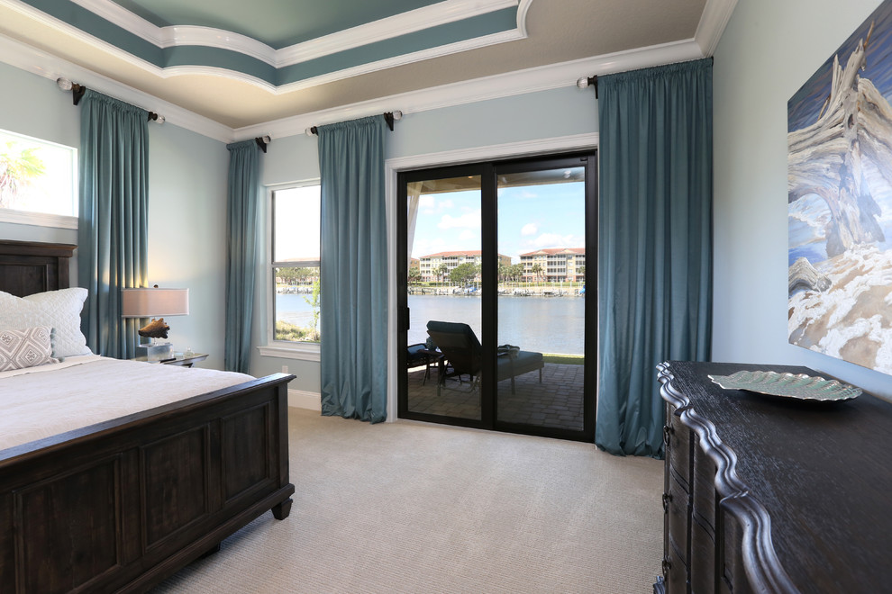 Photo of a large beach style master bedroom in Orlando with blue walls, carpet, no fireplace and beige floor.