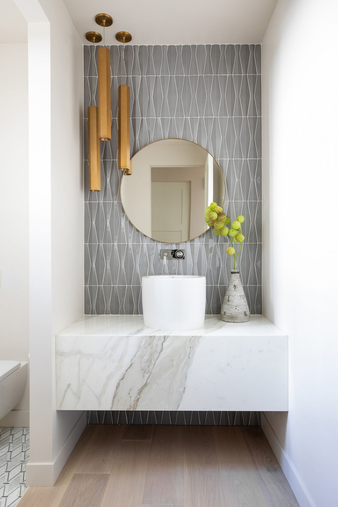 Inspiration for a small contemporary bathroom in Sacramento with white cabinets, a wall-mount toilet, gray tile, ceramic tile, white walls, light hardwood floors, a pedestal sink, marble benchtops, white benchtops, a single vanity and a floating vanity.