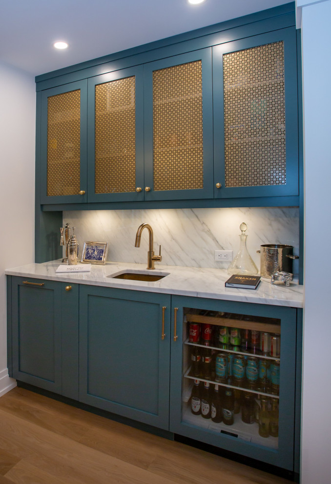 Inspiration for a small beach style single-wall wet bar in Other with an undermount sink, shaker cabinets, green cabinets, white splashback, stone slab splashback, medium hardwood floors, brown floor and white benchtop.