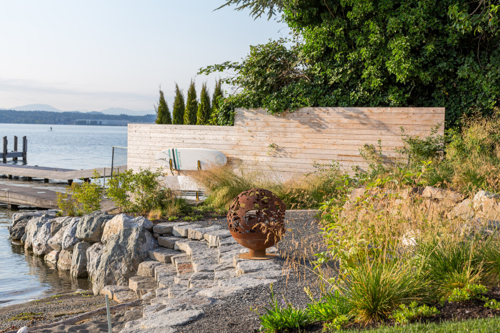 Foto di un grande giardino contemporaneo esposto in pieno sole in estate con un pendio, una collina o una riva, ghiaia e recinzione in metallo