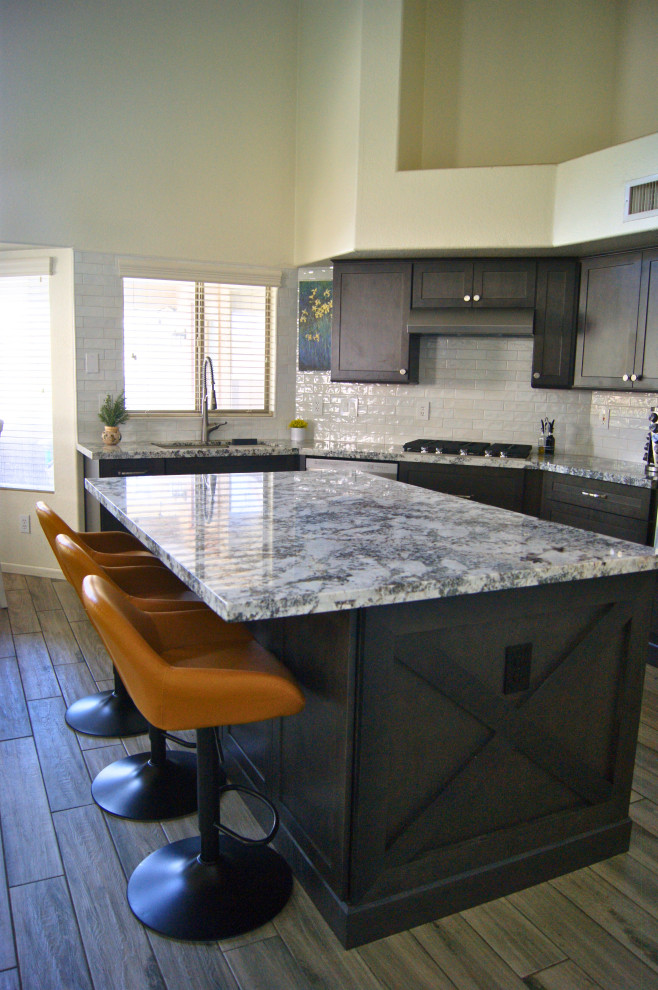 Inspiration for a mid-sized modern l-shaped porcelain tile and gray floor open concept kitchen remodel in Phoenix with an undermount sink, shaker cabinets, brown cabinets, granite countertops, white backsplash, subway tile backsplash, stainless steel appliances, an island and white countertops
