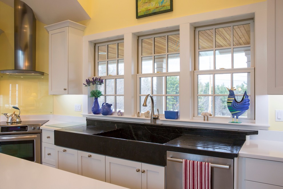 This is an example of a large country u-shaped eat-in kitchen in Boston with a farmhouse sink, flat-panel cabinets, white cabinets, quartz benchtops, stainless steel appliances, light hardwood floors and multiple islands.