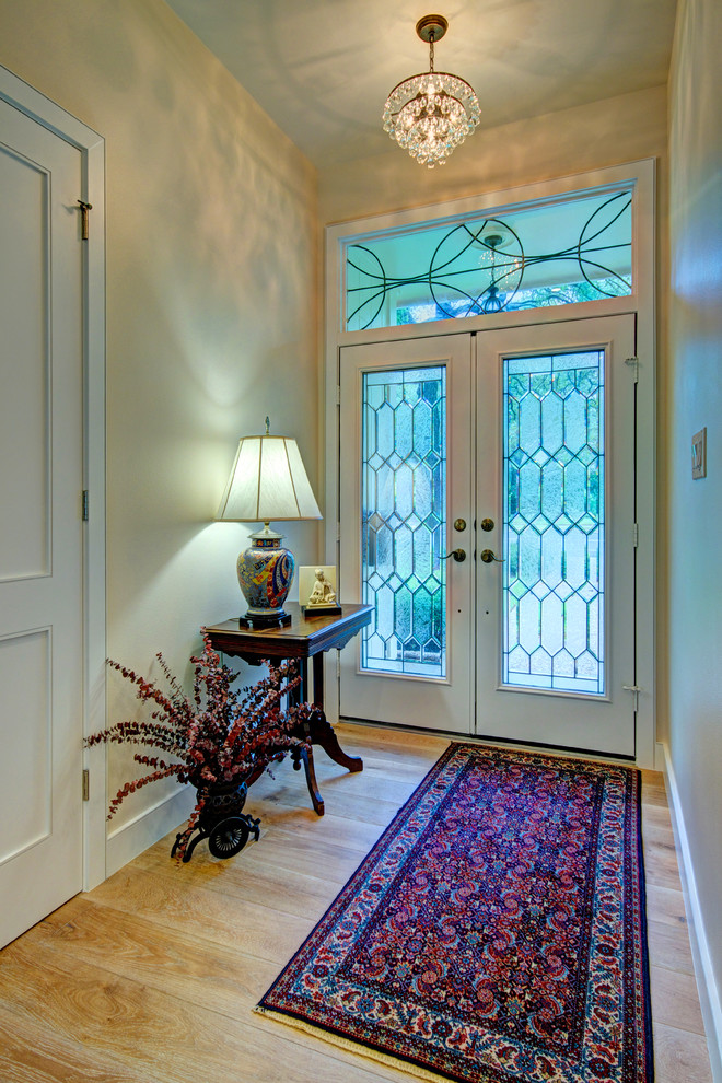 Example of a mid-sized transitional light wood floor foyer design in Austin with beige walls and a white front door
