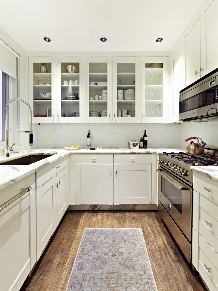 Inspiration for a transitional u-shaped separate kitchen in New York with an undermount sink, shaker cabinets, white cabinets, white splashback, stainless steel appliances and dark hardwood floors.