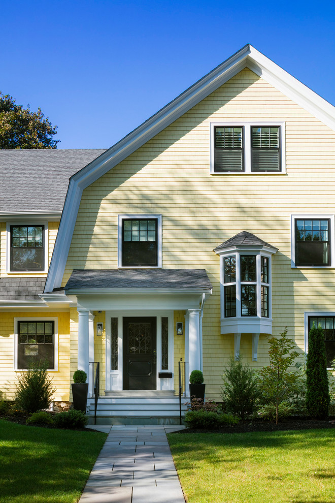 Inspiration for a large traditional three-storey yellow house exterior in Boston with mixed siding, a gambrel roof and a shingle roof.