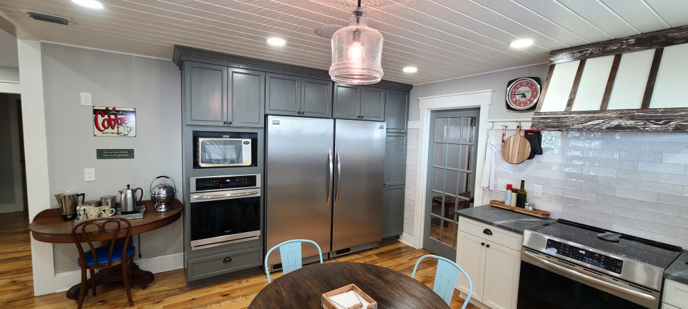 Example of a large u-shaped medium tone wood floor, brown floor and shiplap ceiling eat-in kitchen design with a farmhouse sink, shaker cabinets, gray cabinets, quartz countertops, gray backsplash, stainless steel appliances, a peninsula and black countertops
