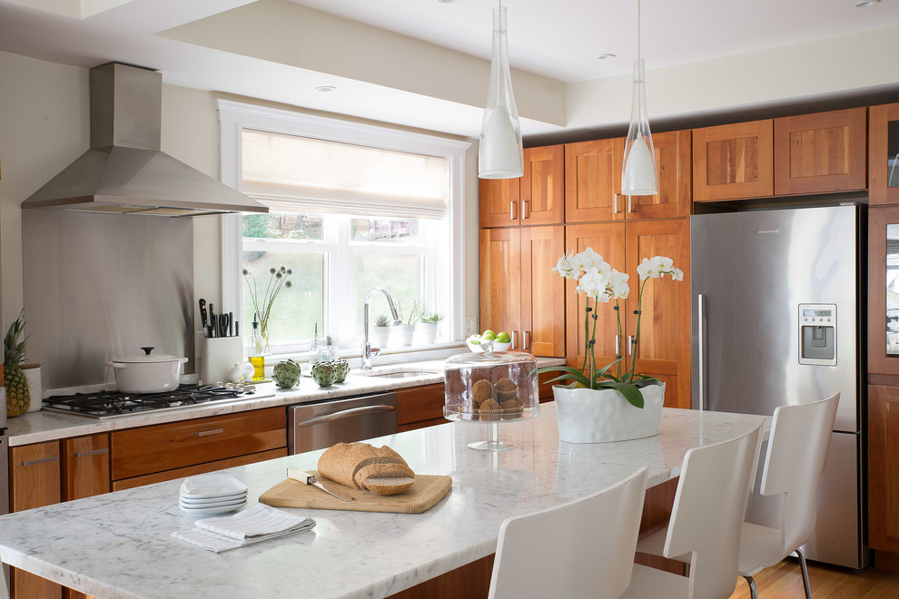 Example of a mid-sized transitional single-wall light wood floor and brown floor kitchen design in Boston with an undermount sink, shaker cabinets, medium tone wood cabinets, marble countertops, stainless steel appliances and an island