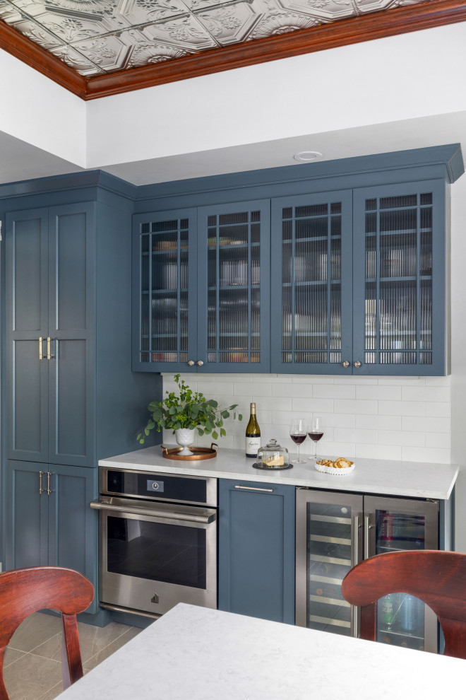 Inspiration for a victorian u-shaped kitchen in Boston with a belfast sink, shaker cabinets, blue cabinets, engineered stone countertops, grey splashback, mosaic tiled splashback, stainless steel appliances, porcelain flooring, a breakfast bar, grey floors, white worktops and a drop ceiling.