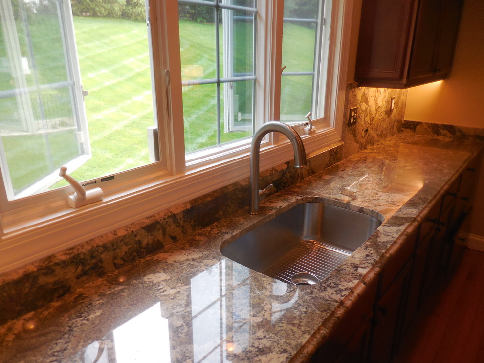Kitchen - mid-sized transitional medium tone wood floor kitchen idea in Baltimore with an undermount sink, medium tone wood cabinets, granite countertops, multicolored backsplash, stone slab backsplash and stainless steel appliances