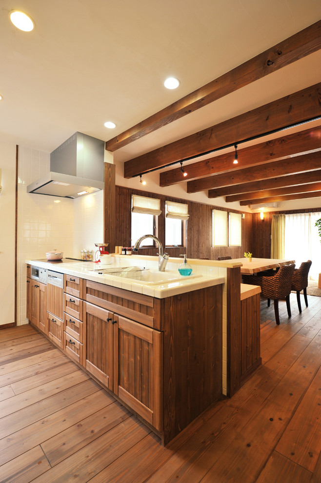 Design ideas for a mid-sized asian open plan kitchen in Other with an undermount sink, open cabinets, brown cabinets, tile benchtops, white splashback, ceramic splashback, stainless steel appliances, dark hardwood floors, no island, brown floor and brown benchtop.