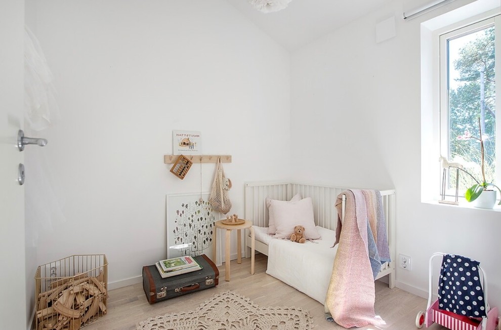Scandinavian kids' bedroom in Gothenburg with white walls, light hardwood floors and beige floor.