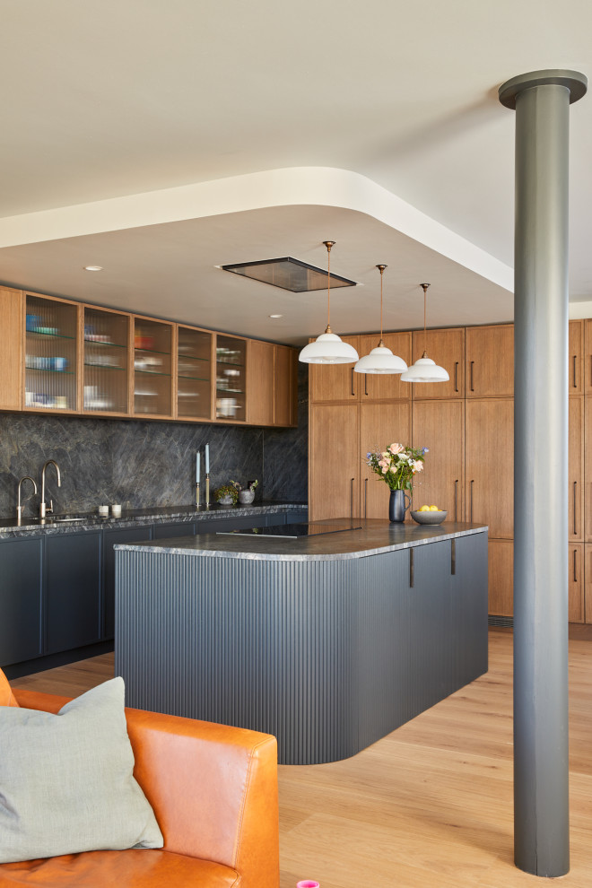 Large contemporary l-shaped open plan kitchen in London with recessed-panel cabinets and with island.