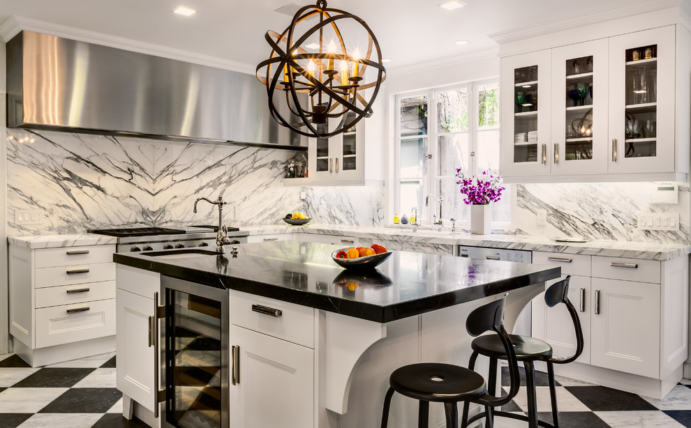 Photo of a mid-sized transitional l-shaped kitchen in Los Angeles with glass-front cabinets, white cabinets, white splashback, marble floors, with island and marble splashback.