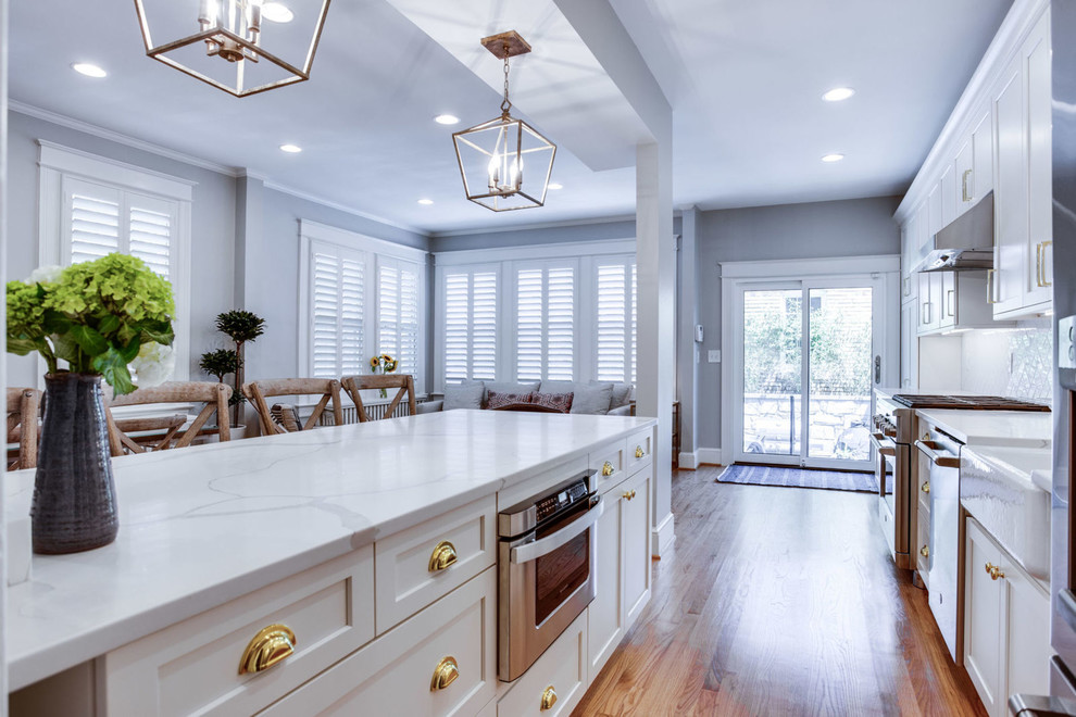 Inspiration for a mid-sized transitional galley light wood floor and beige floor eat-in kitchen remodel in DC Metro with a farmhouse sink, shaker cabinets, white cabinets, quartz countertops, white backsplash, subway tile backsplash, stainless steel appliances, a peninsula and white countertops