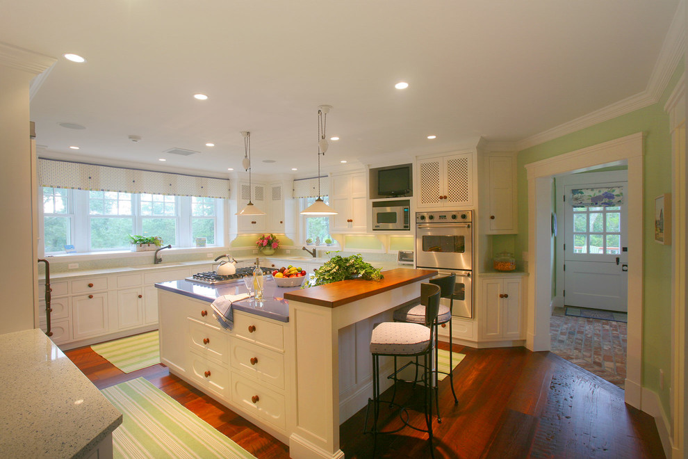 Photo of a large beach style u-shaped eat-in kitchen in Boston with recessed-panel cabinets, white cabinets, green splashback, stainless steel appliances, dark hardwood floors and with island.