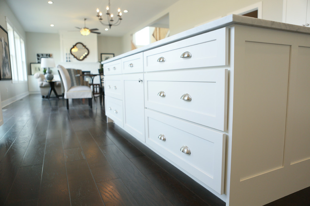 Inspiration for a large transitional u-shaped dark wood floor home design remodel in Chicago with a farmhouse sink, shaker cabinets, yellow cabinets, granite countertops, white backsplash, subway tile backsplash, stainless steel appliances and an island