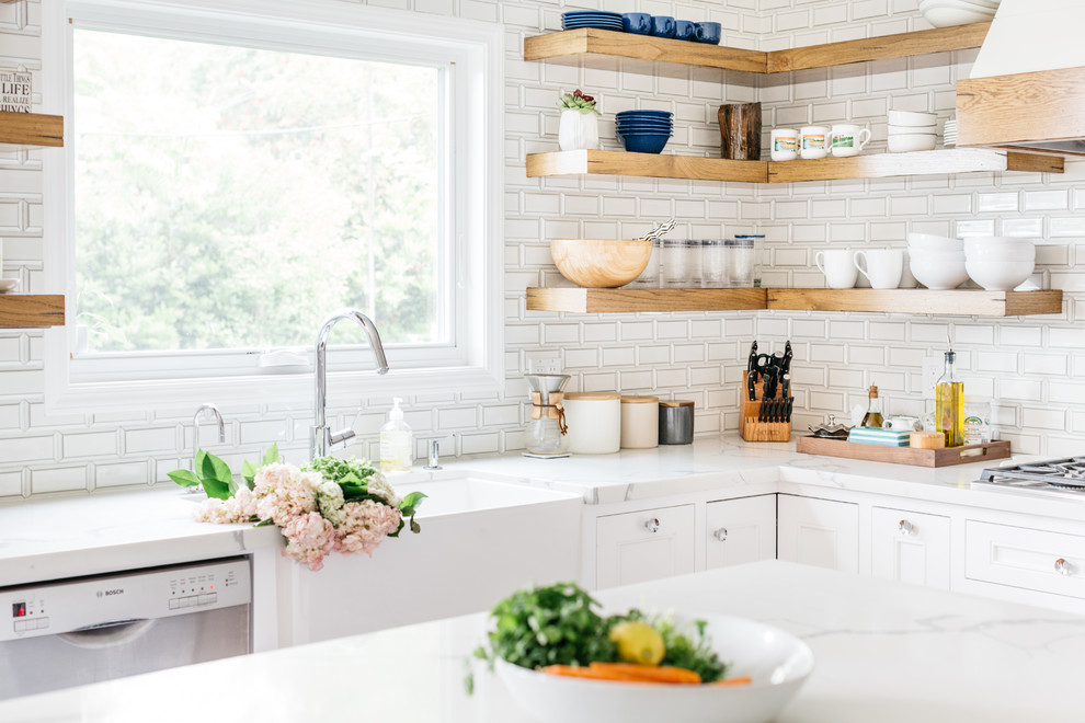 Inspiration for a mid-sized transitional u-shaped medium tone wood floor and brown floor eat-in kitchen remodel in Los Angeles with a farmhouse sink, recessed-panel cabinets, white cabinets, quartzite countertops, white backsplash, subway tile backsplash, stainless steel appliances, an island and white countertops