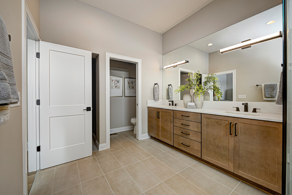 Design ideas for a mid-sized country master bathroom in Indianapolis with shaker cabinets, medium wood cabinets, a one-piece toilet, grey walls, porcelain floors, an undermount sink, engineered quartz benchtops, beige floor, white benchtops, an enclosed toilet, a double vanity and a built-in vanity.