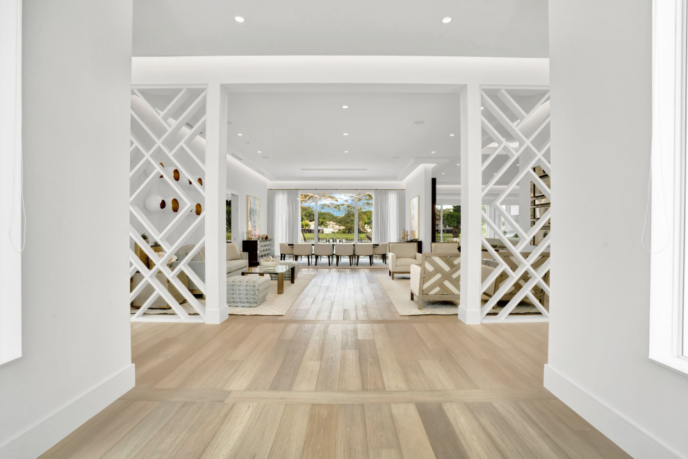 Photo of a large contemporary foyer in Miami with white walls, light hardwood floors, a double front door, a dark wood front door, beige floor and coffered.