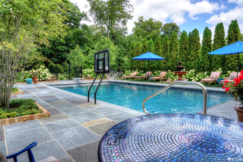 Photo of a mid-sized traditional backyard rectangular lap pool in Chicago with a water feature and natural stone pavers.