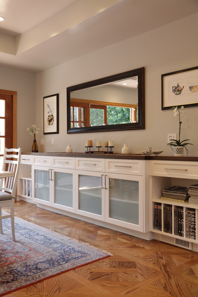 Inspiration for a large transitional u-shaped medium tone wood floor eat-in kitchen remodel in Los Angeles with an undermount sink, recessed-panel cabinets, white cabinets, wood countertops, white backsplash, stone tile backsplash, stainless steel appliances and an island