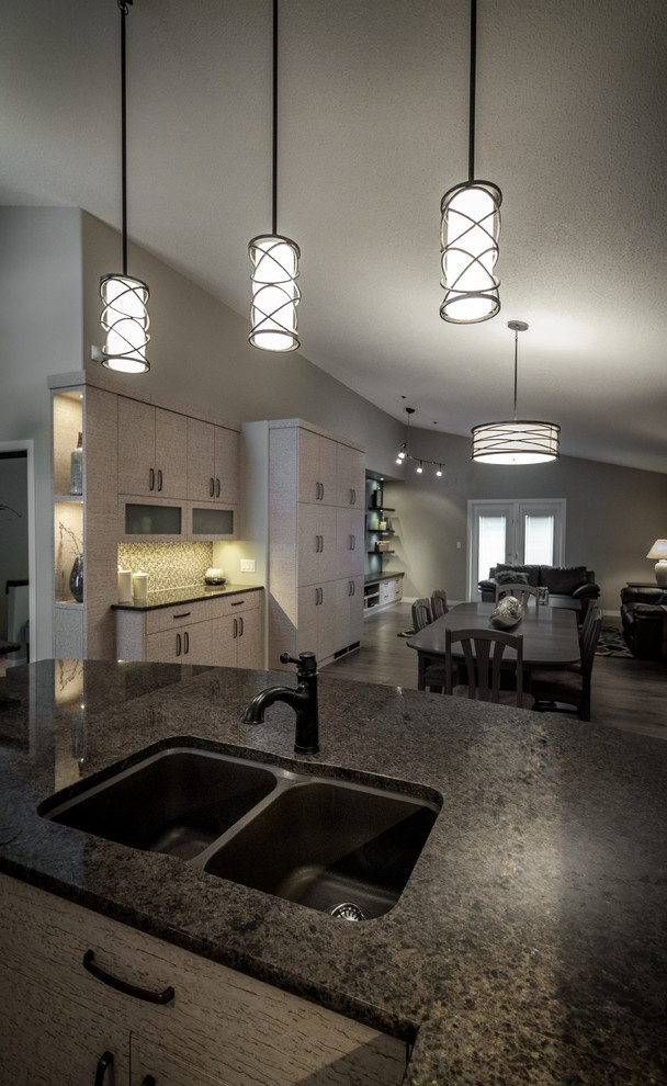 Example of a mid-sized minimalist u-shaped medium tone wood floor and gray floor enclosed kitchen design with a double-bowl sink, flat-panel cabinets, beige cabinets, granite countertops, multicolored backsplash, mosaic tile backsplash, stainless steel appliances and a peninsula