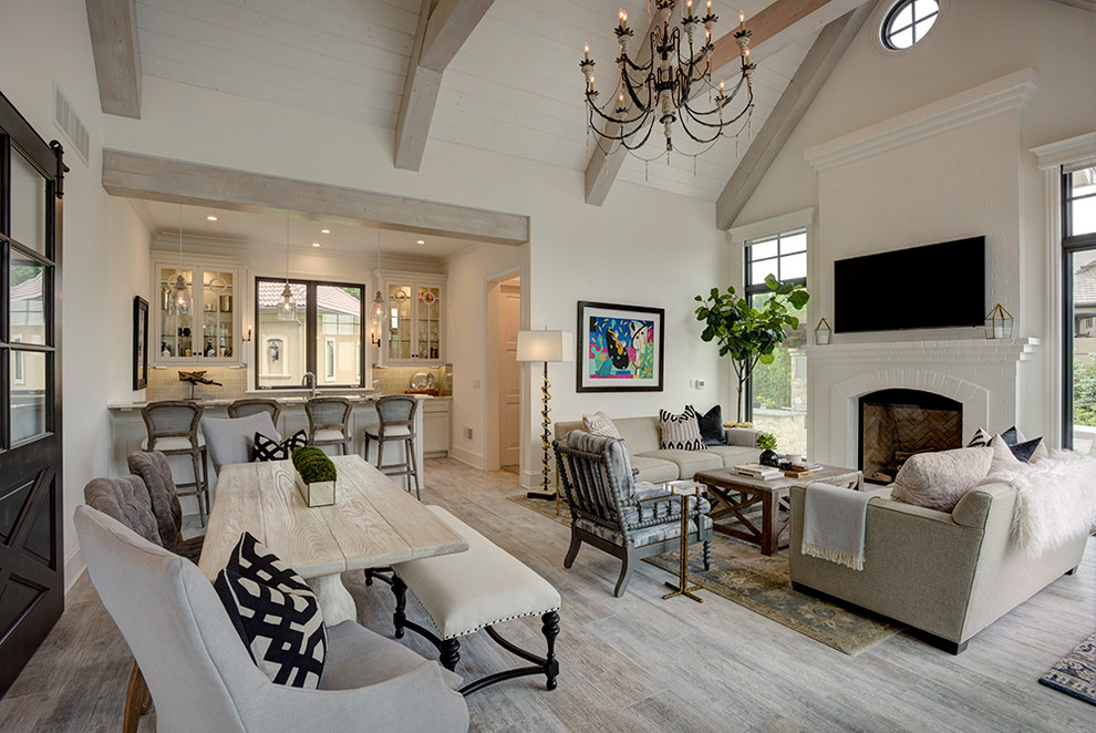 Expansive beach style open concept family room in Kansas City with white walls, ceramic floors, a standard fireplace, a brick fireplace surround and multi-coloured floor.