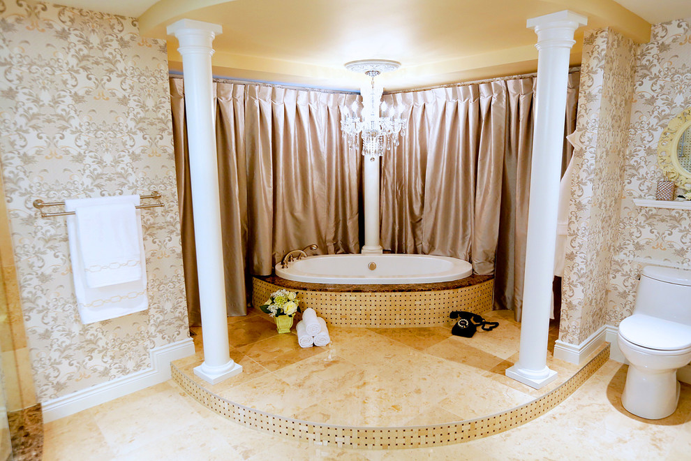 Large traditional master bathroom in Toronto with a drop-in sink, recessed-panel cabinets, distressed cabinets, marble benchtops, a drop-in tub, a corner shower, a one-piece toilet, beige tile, stone tile, beige walls and marble floors.