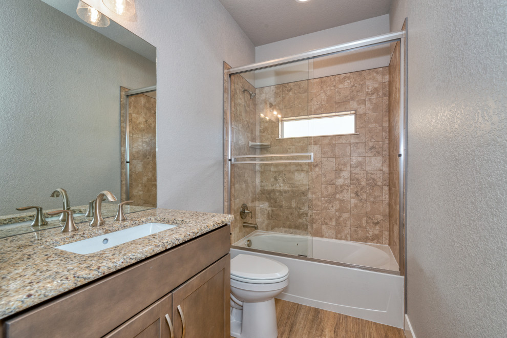 This is an example of a small transitional 3/4 bathroom in Denver with shaker cabinets, grey cabinets, an alcove tub, a shower/bathtub combo, a two-piece toilet, beige tile, ceramic tile, white walls, an undermount sink, granite benchtops, a sliding shower screen, beige benchtops, a single vanity and a built-in vanity.