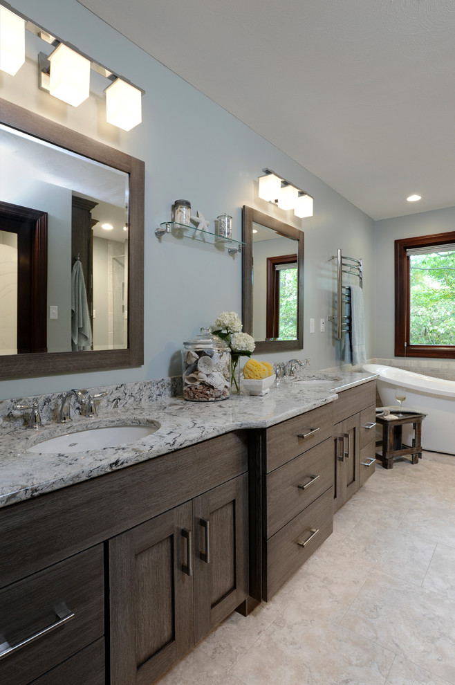 Photo of a large contemporary master bathroom in Cincinnati with an undermount sink, recessed-panel cabinets, grey cabinets, engineered quartz benchtops, a freestanding tub, a corner shower, a two-piece toilet, white tile, porcelain tile, blue walls and vinyl floors.